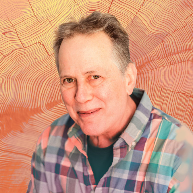 close up picture of the man Bob Chabot with a warm smile, in a colorful checkered shirt with a complimentary orange and yellow wood grain background